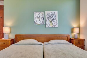 A double bed with a wooden headboard, two bedside lamps, and two abstract wall art pieces.