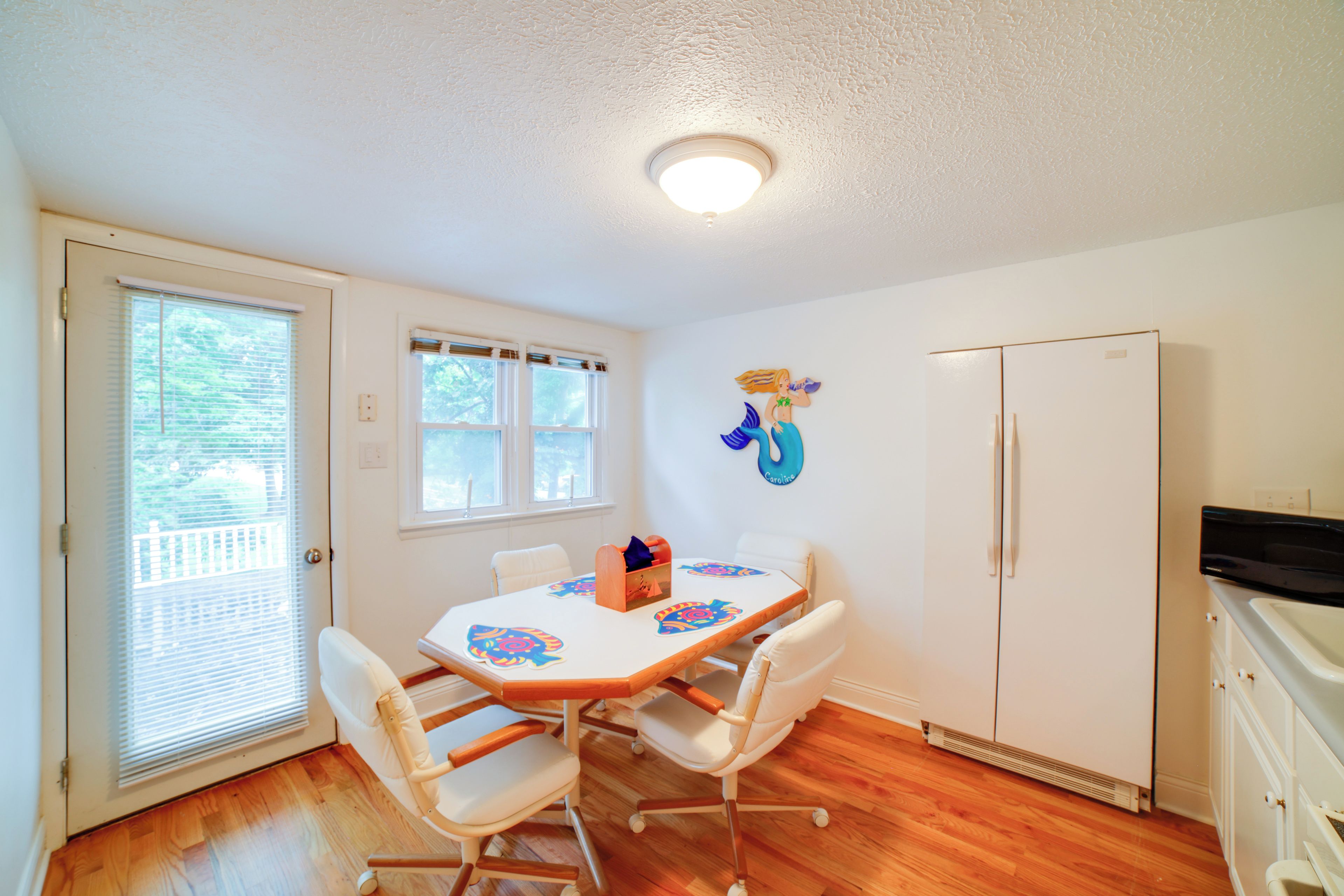 A dining area with a table, chairs, and a refrigerator.