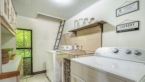 A laundry area with a washing machine, a dryer, and a shelf with jars. - Poolside Playa Carrillo Hideaway, Walk to Beach (Puerto Carrillo)