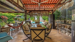 An outdoor patio with a dining table, chairs, a hammock, and a pool in the background. - Poolside Playa Carrillo Hideaway, Walk to Beach (Puerto Carrillo)