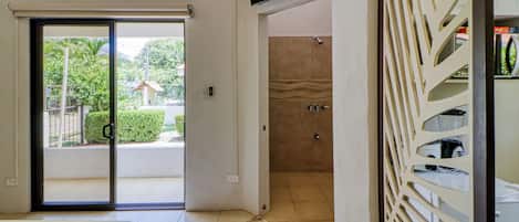 A bedroom with a bed, a shower area, and a television mounted on the wall.