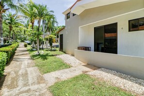 A modern building with a paved pathway, palm trees, and a well-maintained lawn. - Studio w/ Resort-style Pool, Walk to Beach! (Sardinal)