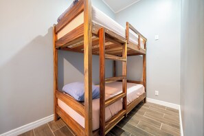 A bunk bed with wooden frames and a mattress, in a room with light-colored walls and a tiled floor. - Shared Pool Access: Updated Apt in Playa Avellanas (Tamarindo)
