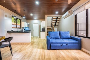 Un interior moderno con cocina, comedor y sala de estar que incluye un sofá.