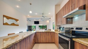 A modern kitchen with wooden cabinets, a granite countertop, and stainless steel appliances. - Modern + Spacious Tamarindo Home w/ Private Pool (Tamarindo)