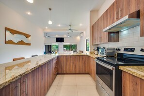 A modern kitchen with wooden cabinets, a granite countertop, and stainless steel appliances.