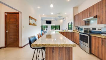 A modern kitchen with a central island, wooden cabinets, and stainless steel appliances.