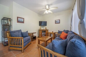 A living room with a sofa, chairs, a coffee table, a TV, and a ceiling fan. - Resort-style Pool: Playa Ocotal Condo Near Beach! (Sardinal)