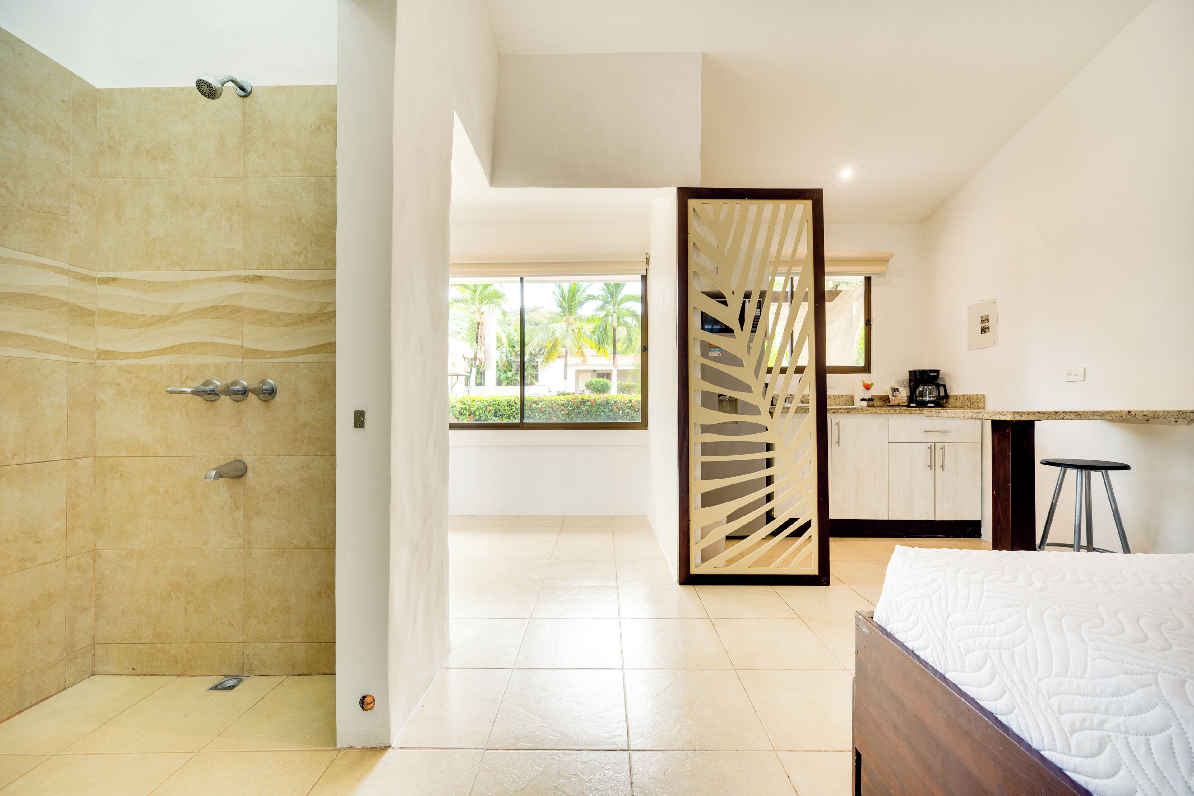 A modern bathroom with a shower, a wooden door, and a view of a garden through a window.