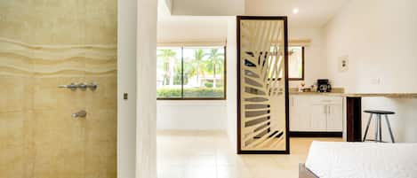 A modern bathroom with a shower, a wooden door, and a view of a garden through a window.