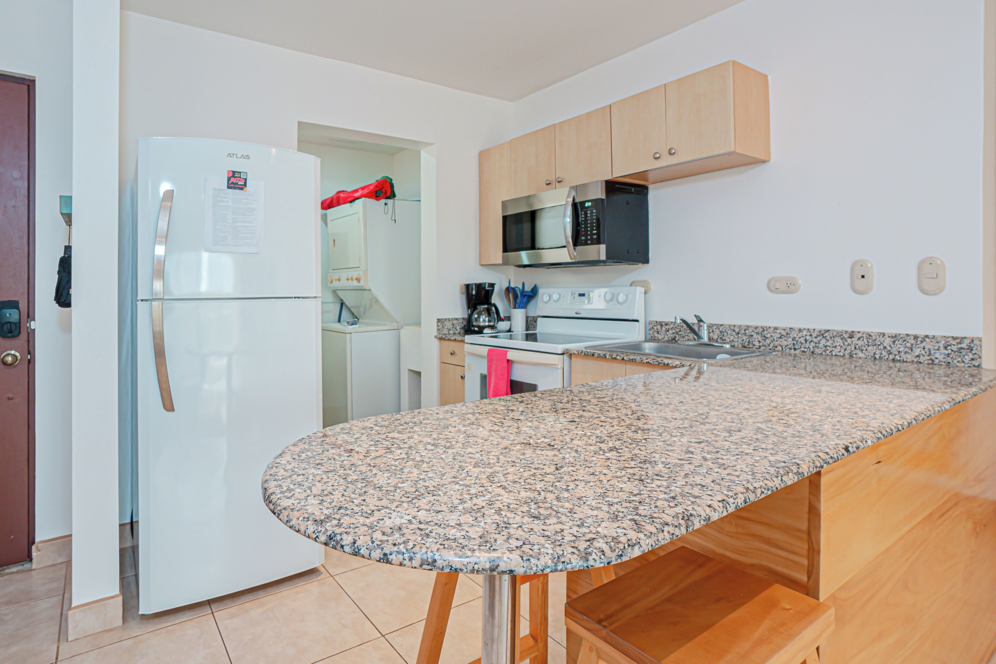 A modern kitchen with a granite countertop, stainless steel appliances, and wooden cabinets.