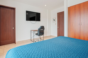 A bedroom with a bed, a desk, a chair, a TV, and two wardrobes. - 3 Mi to Beach: Modern Santa Cruz 2BR Condo (Tamarindo)