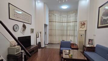 A living room with a chandelier, a sofa, a television, and a staircase.