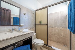 Un bagno con doccia, WC, lavandino e specchio.