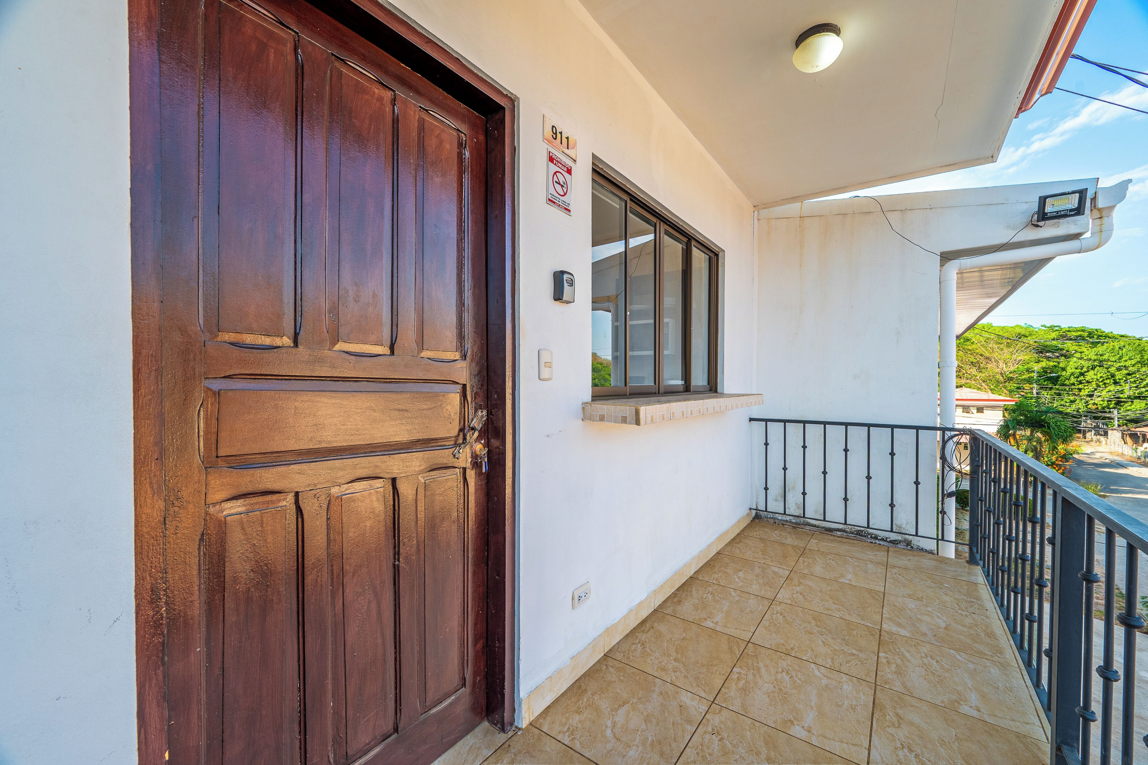 Une porte en bois, une fenêtre et un balcon avec une rambarde en métal.