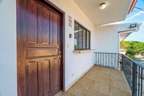 Eine Holztür, ein Fenster und ein Balkon mit einem Metallgeländer.