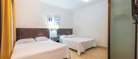 A hotel room with two beds, a nightstand, a lamp, a TV, and a sliding door.