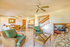 A spacious living area with wicker furniture, a television, and a ceiling fan. - Bahia Pez Vela Resort: Ocean-view Condo (Sardinal)