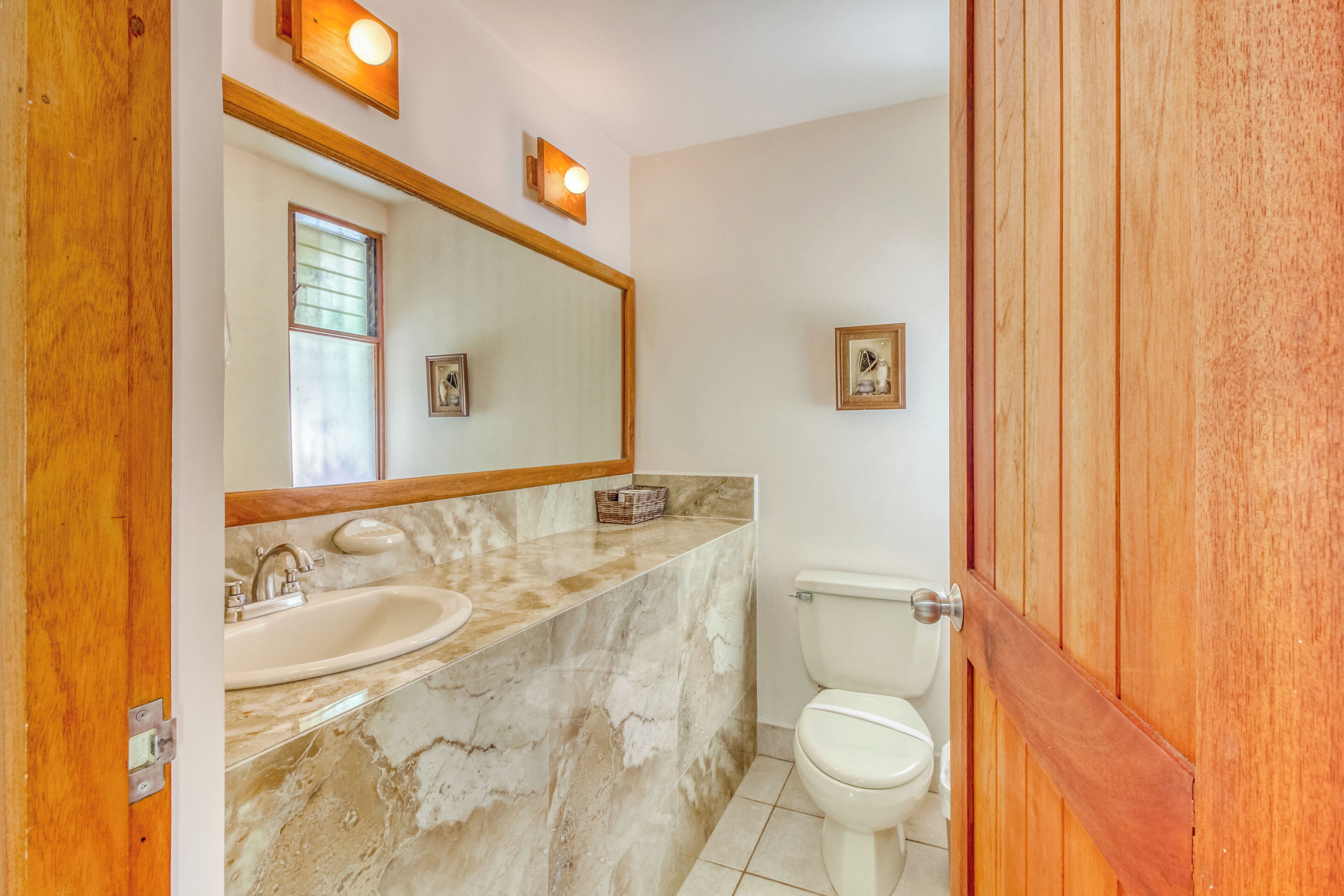 A bathroom with a marble sink, a toilet, and a wooden door.
