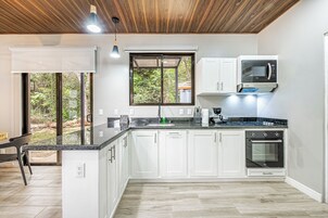 Una cocina moderna con armarios blancos, un microondas integrado y un amplio ventanal.