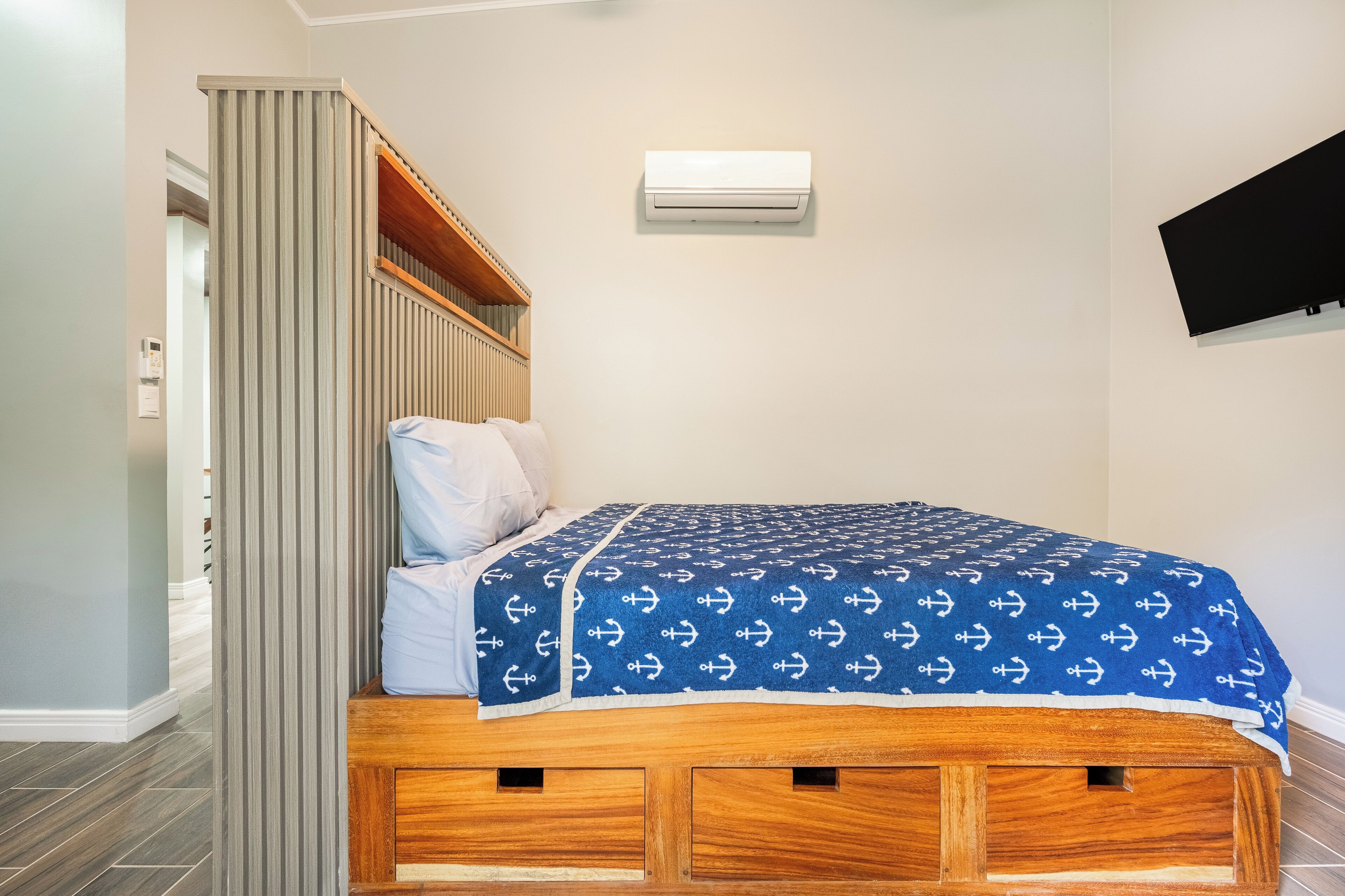 Ein Schlafzimmer mit Bett, Einbauschrank, Wandklimaanlage und Flachbildfernseher.