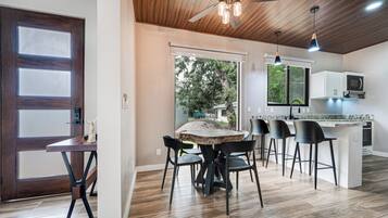 A modern kitchen with a central island, bar stools, and a dining table with chairs.