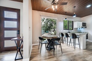 Una cocina moderna con una isla central, taburetes de bar y una mesa de comedor con sillas.