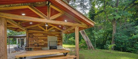Un pavillon en bois doté d’un barbecue intégré et d’un espace détente avec des sièges.