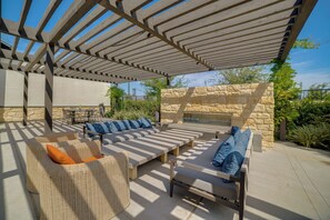 Eine Terrasse im Freien mit Korbmöbeln, Steinmauern und einer Pergola.