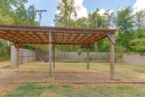 Eine hölzerne Pergola im Garten, im Hintergrund ein Holzzaun.