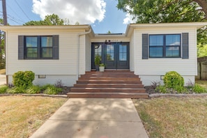 A two-story house with a front entrance, a number plaque, and a front yard with plants.