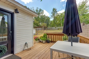 A wooden deck with a table and chairs, a door with a keypad, and potted plants.