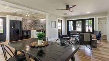 A modern kitchen with a built-in oven, a refrigerator, and a dining area with a black table and chairs.