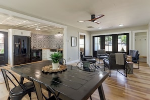A modern kitchen with a built-in oven, a refrigerator, and a dining area with a black table and chairs.
