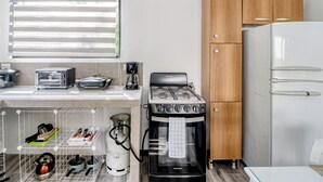Una cucina compatta con fornello, frigorifero e diversi elettrodomestici.