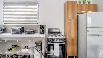 A compact kitchen with a stove, refrigerator, and various appliances.