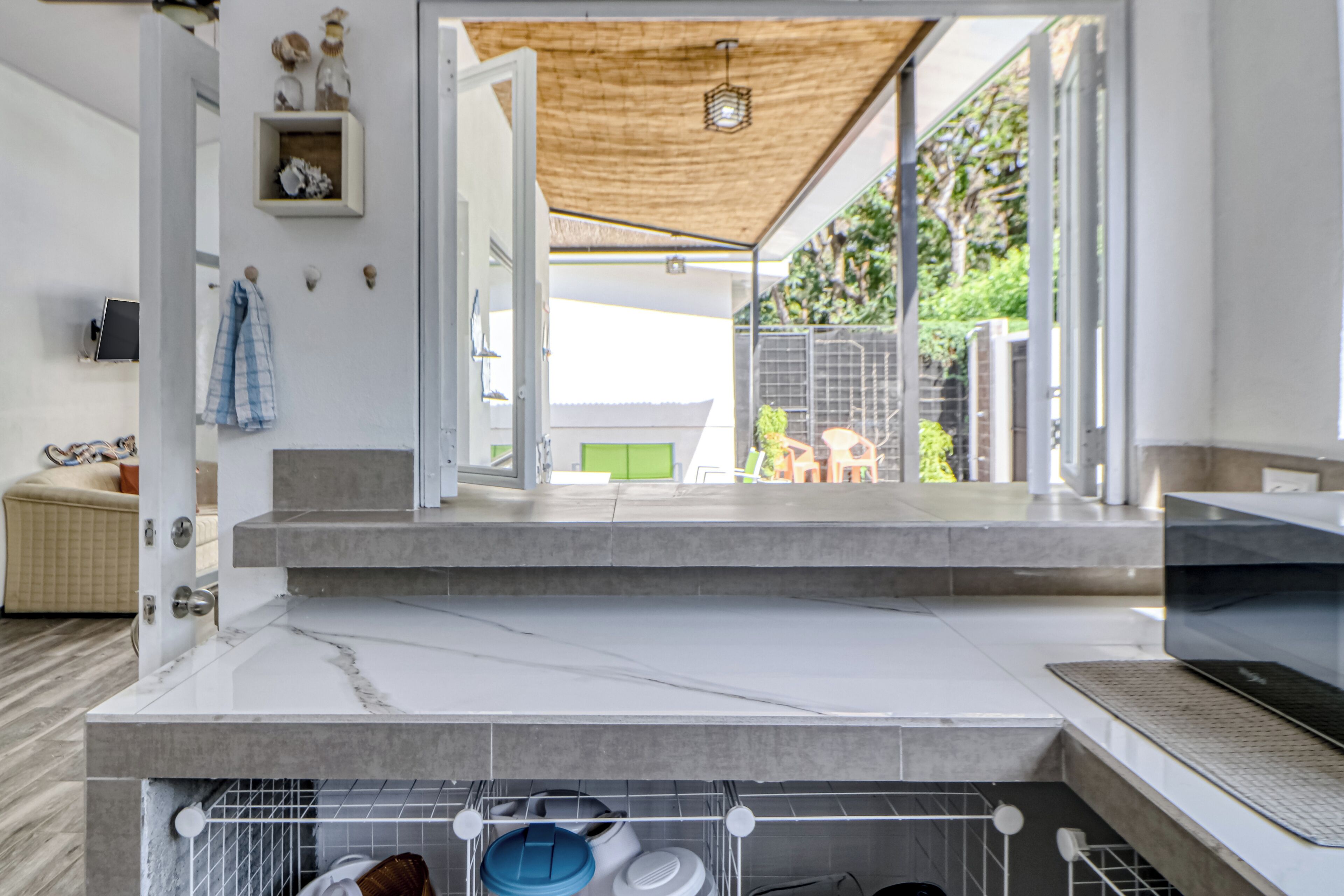 A modern kitchen with a marble countertop, a built-in oven, and a view of the outdoor patio area.