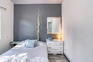 A bedroom with a bed, bedside table, dresser, and a mirror.