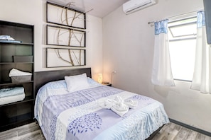 A neatly made bed with a blue and white patterned bedspread, a headboard, and a bedside table with a lamp.