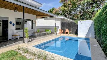 A modern outdoor pool area with a covered seating area and a patio.