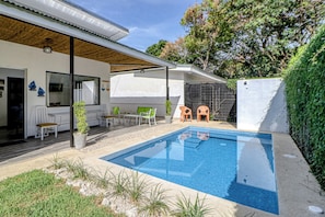 A modern outdoor pool area with a covered seating area and a patio.