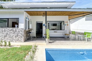 A modern house with a pool, a covered patio, and a bar area.