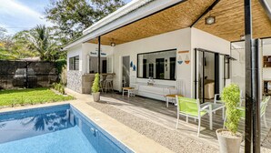 Una casa moderna con piscina, area salotto all'aperto e patio coperto.