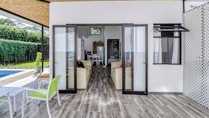 Un interno moderno con una porta vetrata che conduce a una zona soggiorno, una piscina e una sala da pranzo.
