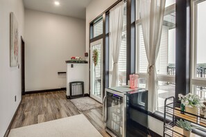 A modern interior with a wooden floor, a glass door leading outside, and a small table with a vase of flowers.