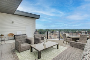 A covered patio with wicker furniture, a welcome sign, and a view of the city. - Rooftop Deck, Great Views! Modern Condo Near Dtwn (Dyersville)