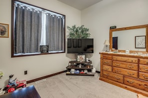 A room with a television on a stand, a dresser with drawers, a window with curtains, and a small plant. - Rooftop Deck, Great Views! Modern Condo Near Dtwn (Dyersville)