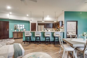 A modern kitchen with bar stools, a dining table, and a living area with a sofa and a coffee table.