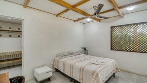 A bedroom with a bed, a small bedside table, a chair, a wardrobe, and a ceiling fan.