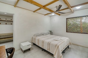 A bedroom with a bed, a small bedside table, a chair, a wardrobe, and a ceiling fan.